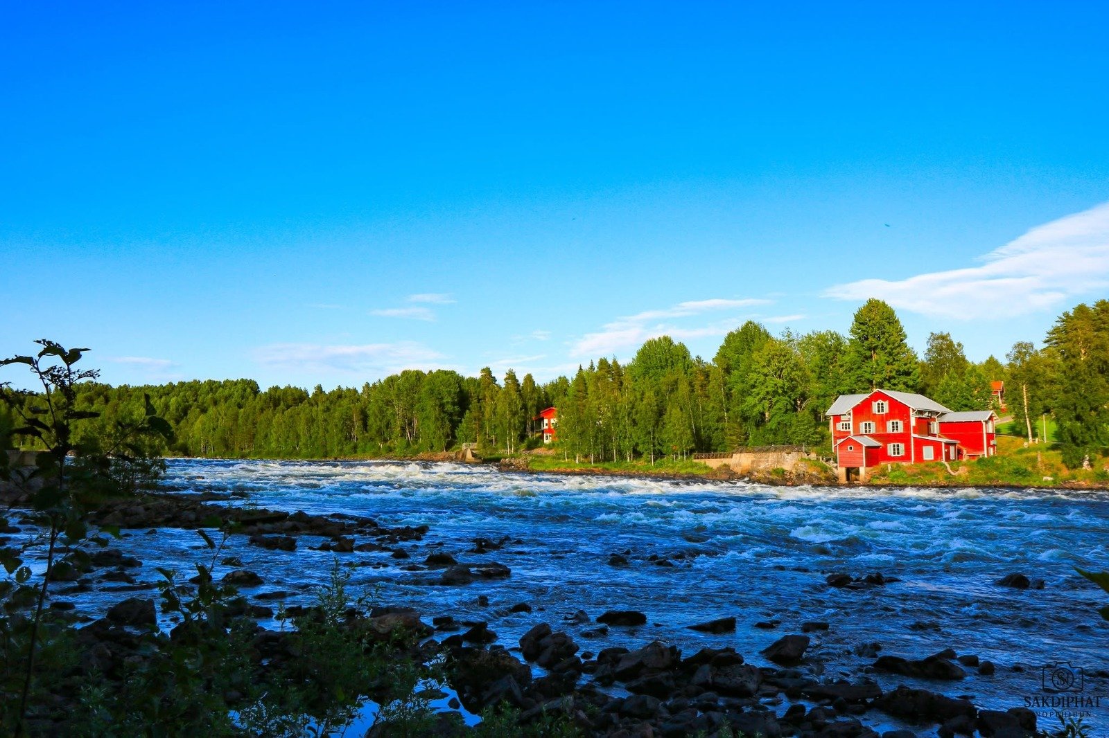 Vindelälven med forsande vatten och den röda kvarnen i Vindeln